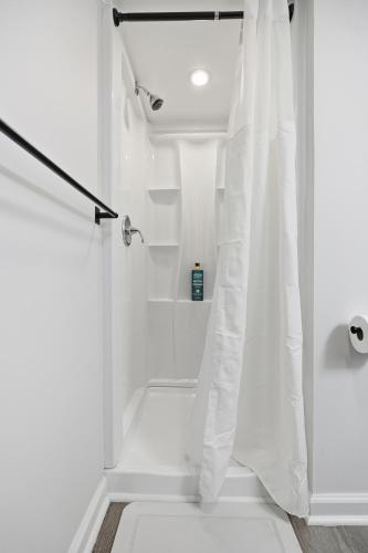 a bathroom with a shower with a white shower curtain at Airport Haven - Cozy 2BR Apt 5 Min Away in Newark