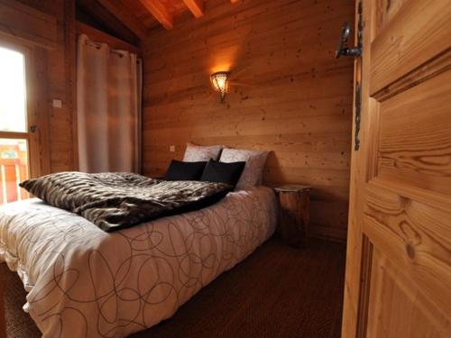 een slaapkamer met een bed in een houten hut bij Chalet neuf pour 6 pers, animaux et parking - FR-1-836-36 in Arâches-la-Frasse