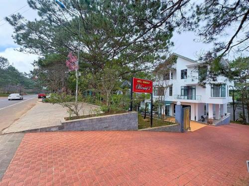 HeniSi 2 Hotel Măng Đen في Kon Von Kla: علامة حمراء على طريق من الطوب بجوار مبنى أبيض