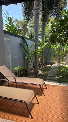 two chairs and palm trees on a wooden deck at Cozy villa - perfect place to stay in Phuket in Ban Saiyuan (1)
