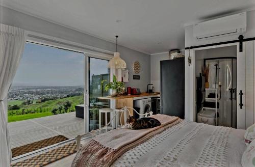 um gato deitado em uma cama em um quarto com cozinha em Stunning Sunsets & Views at Wonderful Wainui em Gisborne