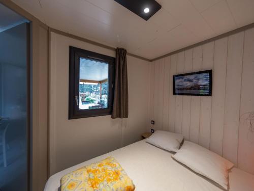 ein kleines Schlafzimmer mit einem Bett und einem Fenster in der Unterkunft Chalet 3 chambres avec piscines chauffées et accès plage à 9km - FR-1-783-24 in Pomérols