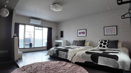 a bedroom with two beds and a large window at Vinyl Stay - spacious local apartment in Osaka