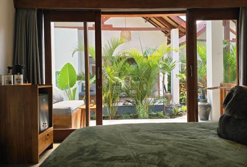 a bedroom with a bed and a balcony with plants at Twiny's in Kuta Lombok