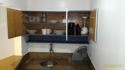 a kitchen with a sink and a shelf with dishes at AP 219 Victory Flat em Tambaú in João Pessoa