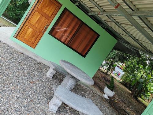 a green house with a bench in front of it at Playa Blanca Puerto Jiménez in Puerto Jiménez