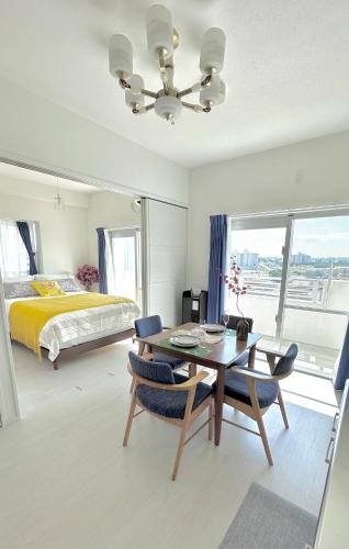 ein Schlafzimmer mit einem Bett, einem Tisch und Stühlen in der Unterkunft SunSea Okinawa Stunning Ocean View 2BR Sleeps 6 20 min from Airport 3 min to Shopping Mall in Urazoe