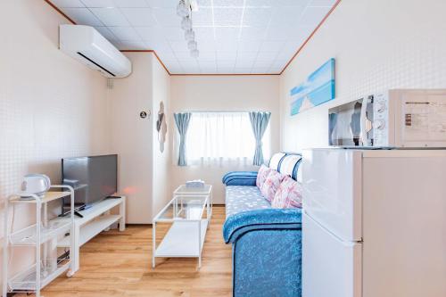 a living room with a couch and a refrigerator at 観光名勝千畳敷徒歩2分 shirahamaペンション千畳嵐 