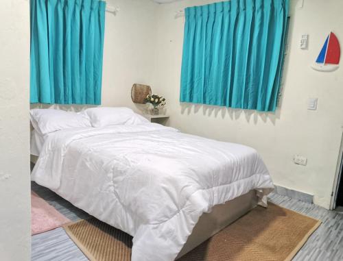 ボカ・チカにあるHabitacion cerca de la Playaの白いベッドと青いカーテンのある寝室