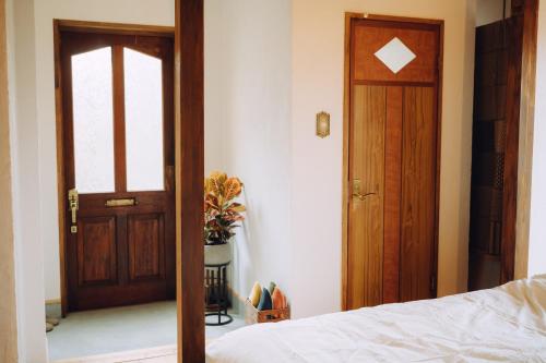 a bedroom with a wooden door and a bed and a door at 海とふれあうための一軒貸し宿オリーブ in Futami