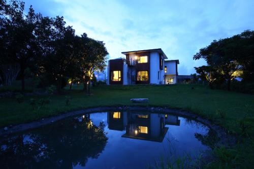 a house with a pond in front of it at 雲起軒民宿 Cloudscape B&B in Jian