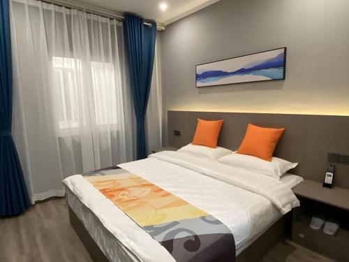 a bedroom with a large bed with orange pillows at Shell Hotel Yancheng Binhai County Renmin Nan Road in Binhai
