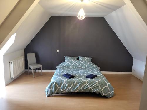 ein Schlafzimmer mit einem Bett und einem Stuhl auf einem Dachboden in der Unterkunft lefevre cottage, Landing beaches house in Saint-Pierre-du-Mont