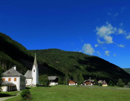 a church in a field in front of a mountain at Apartment Almhaus Innerkrems in Innerkrems