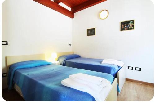 two beds in a room with blue sheets at CasaRiomaggiore "a few steps from the sea" in Riomaggiore