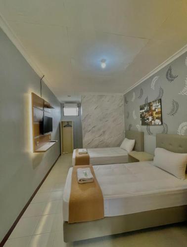 a room with a bed and a couch and a tv at Hotel New Pesona Anggraini in Brujul