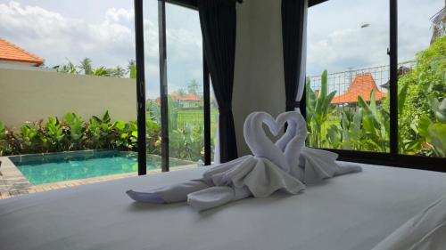 Dos cisnes de papel blanco sentados encima de una cama en Adyatma Ubud, en Ubud