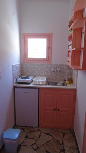 a kitchen with red cabinets and a sink and a window at Vocamvilia Apartments in Kamari