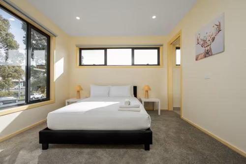 a bedroom with a bed and two windows at Fantastic Large Family Home, 6 Mins to Melbourne Airport in Melbourne