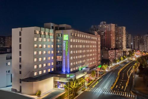 a building with a lit up sign in a city at Holiday Inn Express Shanghai Changyang Road by IHG in Shanghai