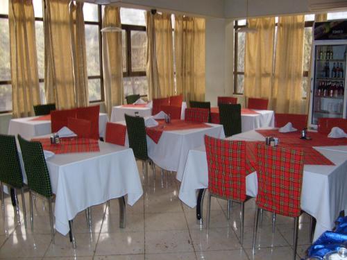 a dining room with white tables and red chairs at Panama Inn Moshi in Moshi