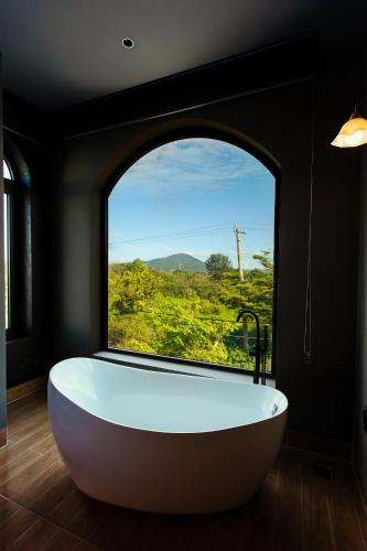 a bath tub in a room with a large window at One and Only Hotel - Đức Trọng in Lien Khuong Airport