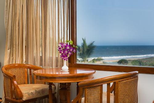 a table with a vase of flowers on top of a table at Ideal Beach Resort in Mahabalipuram