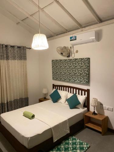 a bedroom with a bed with white sheets and blue pillows at Villa Peace & Plenty in Galle