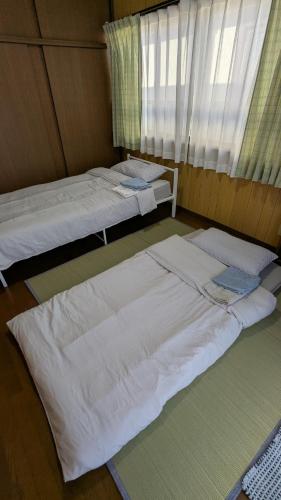 two beds sitting in a room with a window at いちごハウス in Zushi