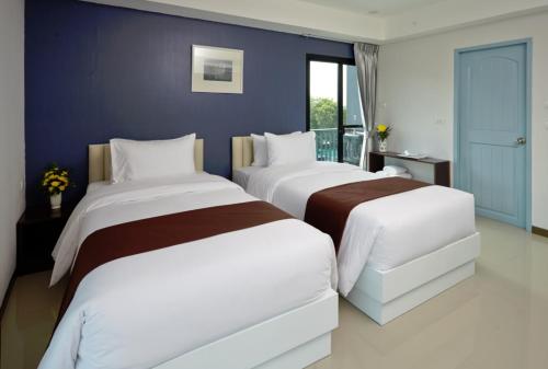 two beds in a room with a blue wall at Casa Residence Hotel in Bangkok