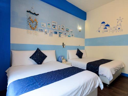two beds in a room with blue and white walls at 花蓮市綠宿民宿 in Hualien City