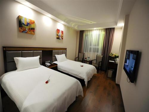 a hotel room with two beds and a flat screen tv at GreenTree Inn Meizhou Meijiang District Wanda Plaza Hotel in Meizhou