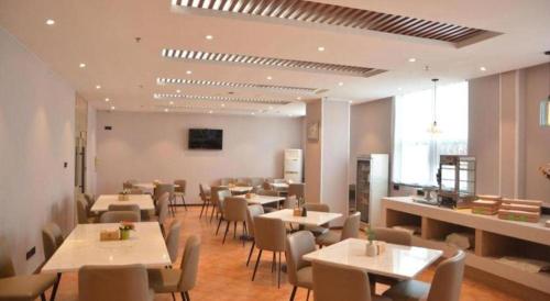 a restaurant with tables and chairs in a room at GreenTree Inn Xuzhou High Speed Railway Station Express Hotel in Xuzhou