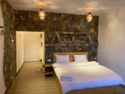 a bedroom with a bed and a stone wall at Panorama Guest House Jabal Shams in Sa‘ab Banī Khamīs