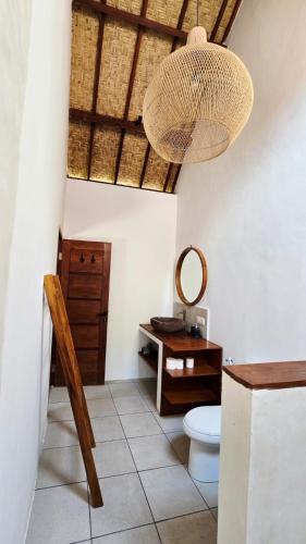 a bathroom with a toilet and a table and a chandelier at Twiny's in Kuta Lombok