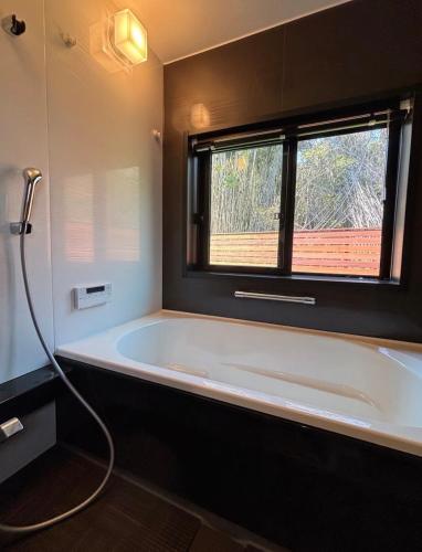 a bathroom with a bath tub with a window at ドッグラン付き一棟貸別荘- Ilio a kai イリオアカイ in Jōnouchi