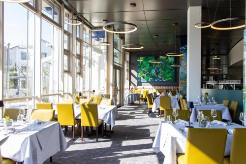 a restaurant with white tables and yellow chairs at Best Western Plus Palatin Kongresshotel in Wiesloch