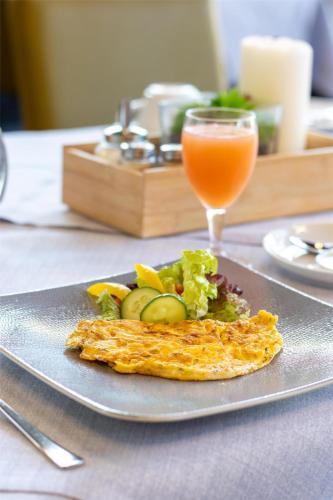 a plate of food with an omelet and a drink at Best Western Plus Palatin Kongresshotel in Wiesloch