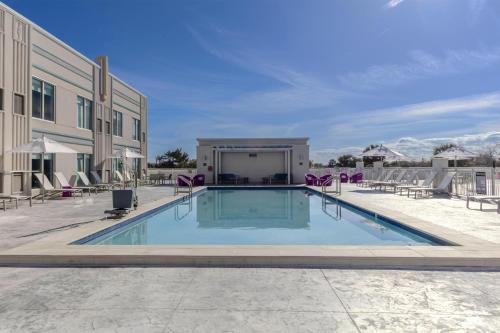 a swimming pool with chairs and a building at Hyatt Place St Augustine Vilano Beach in St. Augustine