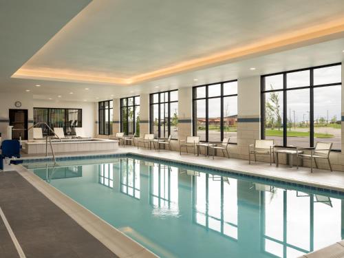 a swimming pool with chairs and tables in a building at Hyatt Place Billings in Billings