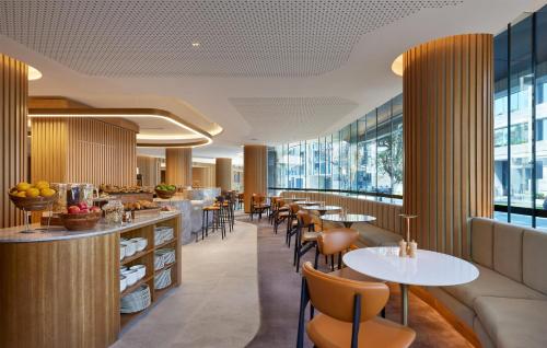 a restaurant with tables and chairs and windows at Hyatt House South Melbourne in Melbourne