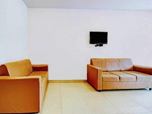 two chairs and a couch in a room with a tv at Hotel O Meridian Grand in Shamshabad