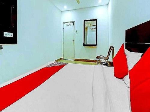 a bedroom with a red and white bed and a mirror at Hotel O Meridian Grand in Shamshabad