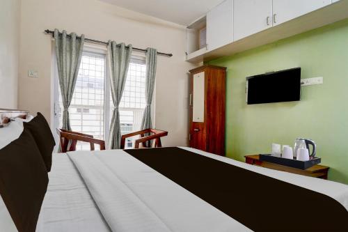 una habitación de hotel con una cama y un televisor en Super Hotel O Central Zone Vishwanathapuram Formerly Green Nest, en Coimbatore