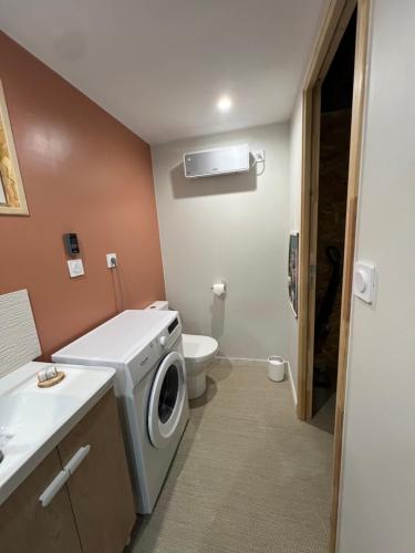 une salle de bains avec lave-linge et toilettes dans l'établissement Gîte du Moulin, à Commer