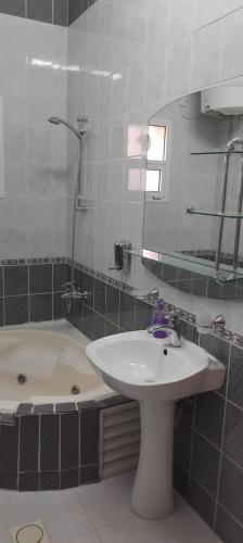 a bathroom with a sink and a tub and a mirror at House Al Ain - 9 in Al Ain