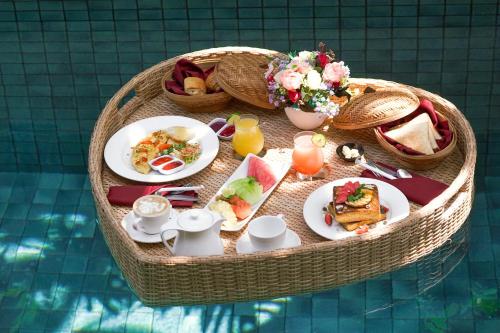 a table with plates of food on top of a pool at The Kasih Villas & Spa in Seminyak