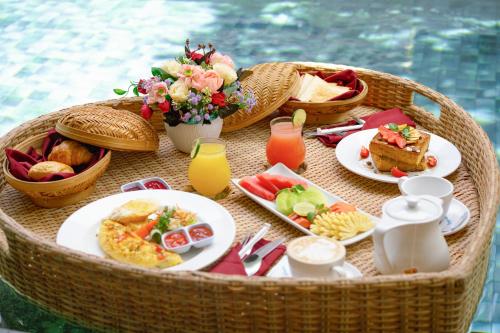 a picnic table with breakfast foods and drinks on it at The Kasih Villas & Spa in Seminyak