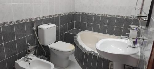 a bathroom with a toilet and a sink and a tub at House Al Ain - 9 in Al Ain