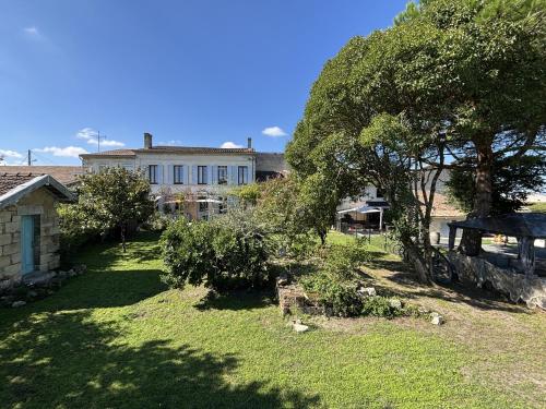 een tuin met een huis en een boom bij Maison JEROBOAM in Saint-Estèphe
